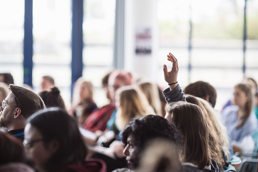 During a lecture: all participants listen to the contribution of the lecturer and someone raises his hand to ask a question 