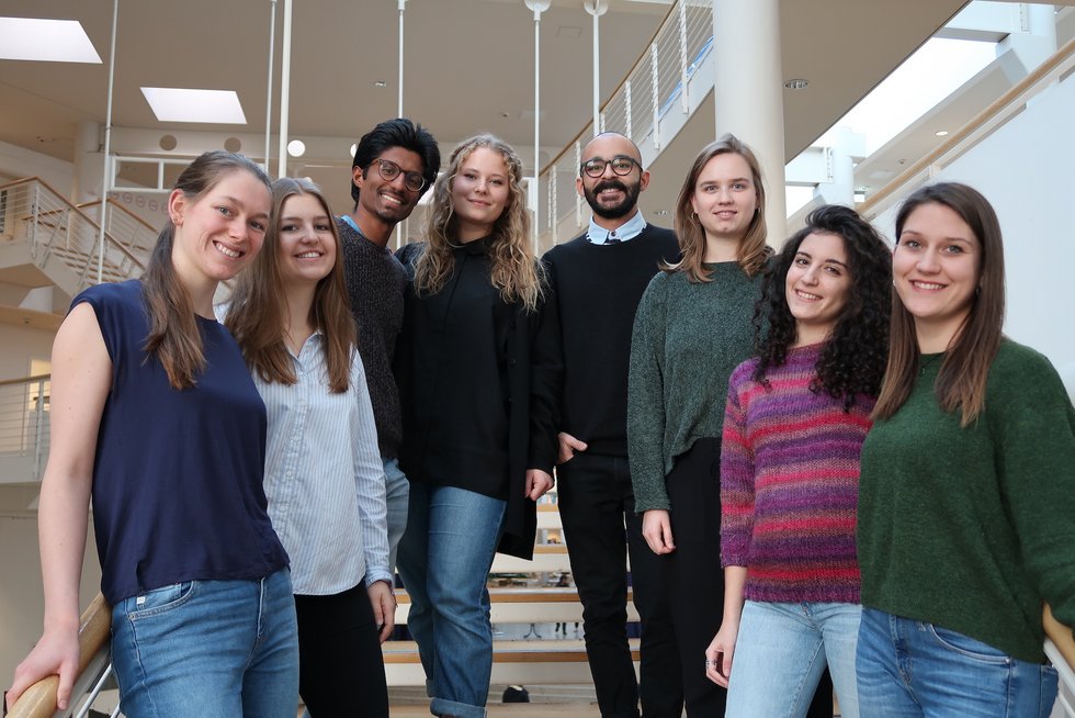 You can see 8 members of the organizing team standing on stairs next to each other and smiling into the camera