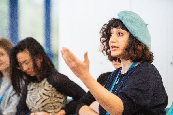 A female participant is gesturing while talking to the lecturer